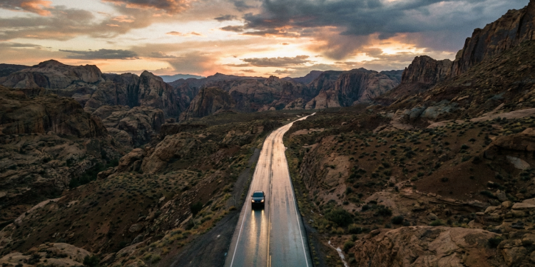 Firefly Gemini Flash A wide, expansive aerial shot of a long, dark asphalt road cutting through an op