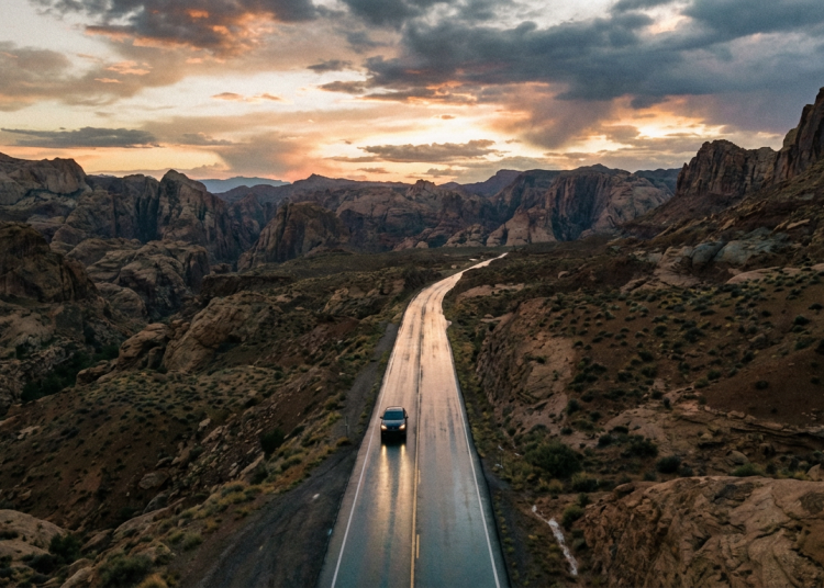 Firefly Gemini Flash A wide, expansive aerial shot of a long, dark asphalt road cutting through an op